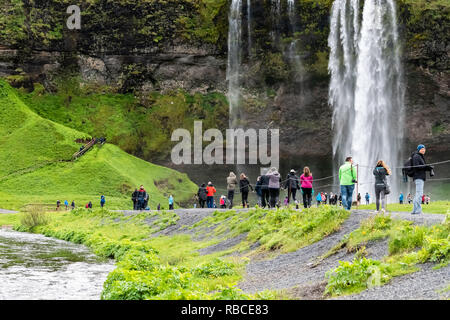 Seljalandsfoss, Island - 14. Juni 2018: Wasserfall mit Wasser von Klippe in Grün bemoosten Sommer felsige Landschaft und Menschen zu Fuß auf den Weg durch die w Stockfoto