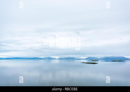 Antenne Landschaft hohe Betrachtungswinkel und der friedlichen, ruhigen und friedlichen fjord Wasser Atlantik mit Bergen im kleinen Fischerdorf Stadt namens Höfn in Stockfoto