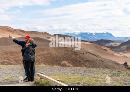 Hverir, Island - 16. Juni 2018: Landschaft Blick auf Berg in Krafla in der Nähe von Mývatn bei bewölkten Tag und Paar unter selfie Bild mit snowcap Stockfoto