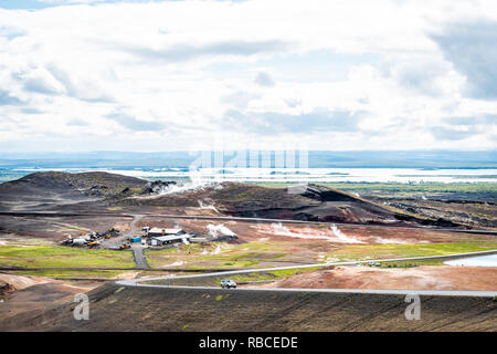 Reykjahlid, Island - 16. Juni 2018: Landschaft hohe Betrachtungswinkel des Sees Myvatn und Fumarolen Dampföffnungen bei bewölkten Tag und Auto auf der Straße Autobahn Stockfoto