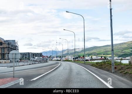 Akureyri, Island - 16. Juni 2018: Stadtbild Straßenbild Blick auf die große Stadt Fischerdorf mit Fjord und die leere Straße, bei der die Zeile der Laternen. Stockfoto
