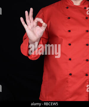 Koch in roter Uniform zeigt eine Geste der Zustimmung mit der rechten Hand und alles ist in Ordnung Stockfoto