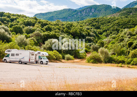 Paralia, Griechenland - 12. Juni 2013: Malerische Aussicht auf zwei Wohnmobile Wohnmobile auf dem Parkplatz unter den hohen und grünen Bergen geparkt auf dem Weg Stockfoto