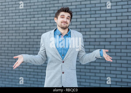 Ich weiß es nicht. Portrait von verwirrt aussehenden bärtigen Mann im lässigen Stil stehen, hob die Arme und Kamera mit Fragwürdigem Gesicht. indoor Studio Stockfoto