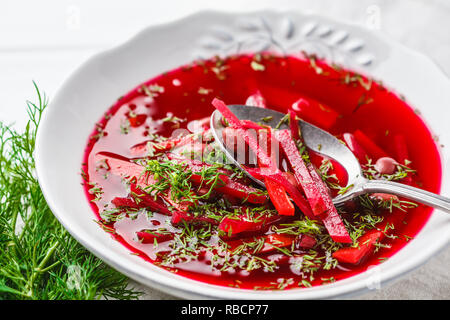 Vegetarische Zuckerrüben-Suppe (Borschtsch) mit Bohnen und Gemüse in eine weiße Platte auf einem weißen Holz- Hintergrund. Stockfoto