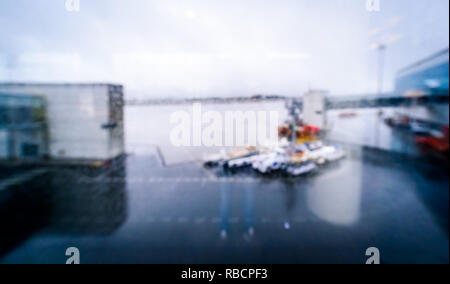 Verschwommene Sicht durch Flughafen Terminal Fenster über der Anzeige der Start- und Landebahn. Defokussierten Bild des regnerischen Tag bei leeren Flughafen Santiago. Stockfoto