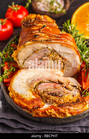 Klassische italienische gebackenes Spanferkel mit Orangen. Gebackenes Schweinefleisch auf einem dunklen Hintergrund. Italienische Küche Konzept. Stockfoto