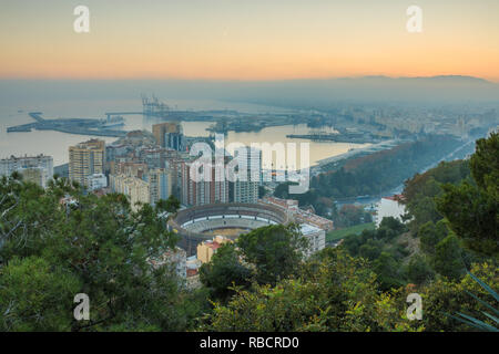 Spanische Stadt Malaga bei Sonnenuntergang. Hafen und der Altstadt mit einem Bull Ring von oben. Gebäude und Schiffe im Hafen gesehen werden kann. in der backgroun Stockfoto