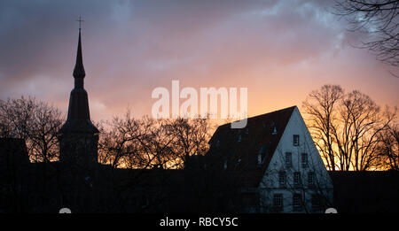 09. Januar 2019, Niedersachsen, Osnabrück: Die Sonne geht hinter die Evangelisch-lutherische Kirche St. Katharina (l). Foto: Friso Gentsch/dpa Stockfoto