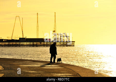 Blackpool, Großbritannien. 9 Jan, 2019. Silhouette der Mann den Hund entlang der Promenade in der Nähe der Pier auf einer ungewöhnlich ruhigen Tag im Januar. Credit: Kevin Walsh/Alamy leben Nachrichten Stockfoto