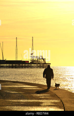 Blackpool, Großbritannien. 9 Jan, 2019. Silhouette der Mann den Hund entlang der Promenade in der Nähe der Pier auf einer ungewöhnlich ruhigen Tag im Januar. Credit: Kevin Walsh/Alamy leben Nachrichten Stockfoto