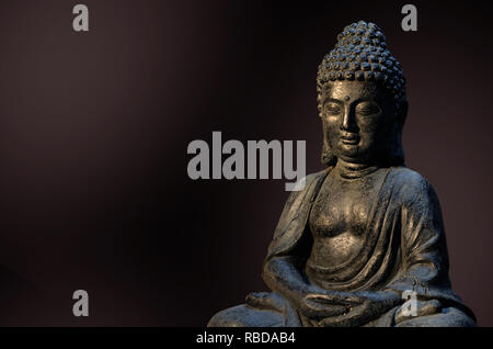 Buddha Statue in der Meditation sitzen Stellen gegen den dunklen Hintergrund. Stockfoto