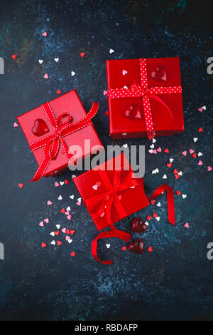 Geschenk Red Boxen mit roter Schleife Schleifen und Herzen auf dunklem Hintergrund für Valentines Tag. Stockfoto