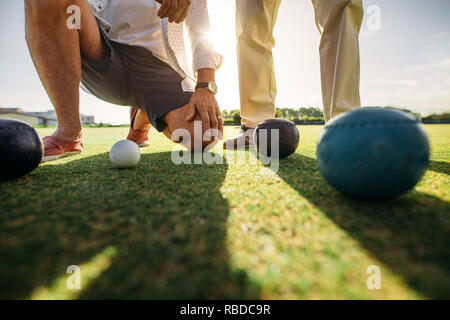 Boden geschossen von zwei Männern, die Position der Boccia. 7/8 shot der Männer betrachten die Boule das Ergebnis des Spiels zu sehen. Stockfoto