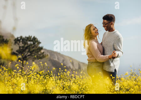 Glückliche junge Mann und Frau tanzen im Freien. Paar in Liebe das Tanzen in der Wiese von gelben Blumen. Stockfoto