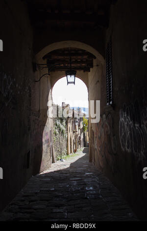 Italien, Arezzo - 12. März 2017: mit dem Blick durch einen Bogen auf einer schmalen Straße von Arezzo an einem sonnigen Tag am 12. März 2017, Toskana, Italien. Stockfoto