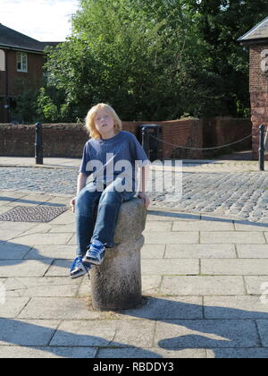 Junge Junge sitzt auf einer steinernen Säule Stockfoto