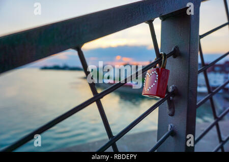 Rotes Vorhängeschloss mit Herz hängen an einem Geländer einer Brücke Stockfoto