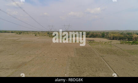 Strommasten Stromversorgung Lager über die ländliche Landschaft. luftaufnahme Strommasten und Hochspannungsleitungen Java, Indonesien. Hohe Spannung Metall post, Turm. Elektrische Stromleitungen über Bäume. Stockfoto