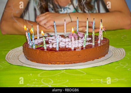 Junges Mädchen ist die Kerzen auf dem Geburtstagskuchen zu blasen Stockfoto