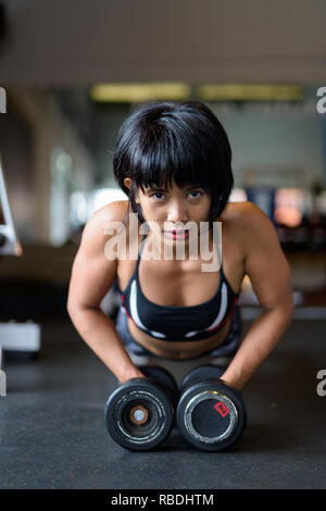 Fitness Frau tun Plank mit Hanteln in der Turnhalle Stockfoto