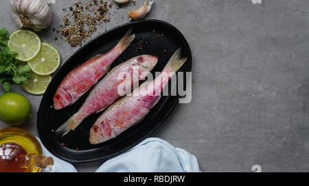 Frischer Fisch Rotbarbe mit Kalk und Gewürze auf einem Schneidebrett Top View Stockfoto