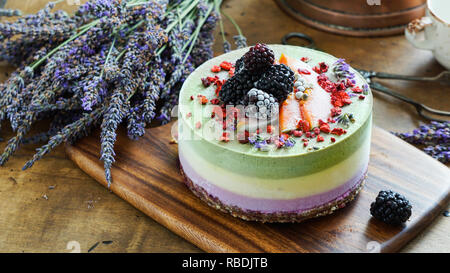 Vegan raw Käsekuchen mit Heidelbeere, Kirsche, Matcha Tee, Orange, cashew Creme, coconut Butter und Kokosmilch und Basis aus Mandeln, Termine und getrocknete Aprikosen, Haferflocken, lyophilisated Berry Stockfoto