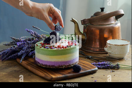 Vegan raw Käsekuchen mit Heidelbeere, Kirsche, Matcha Tee, Orange, cashew Creme, coconut Butter und Kokosmilch und Basis aus Mandeln, Termine und getrocknete Aprikosen, Haferflocken, lyophilisated Berry Stockfoto