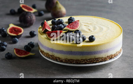 Vegan raw Käsekuchen mit Heidelbeeren und Feigen, cashew Creme, coconut Butter und Kokosmilch und Basis aus Mandeln, Termine und getrocknete Aprikosen, Haferflocken, lyophilisated Berry Stockfoto