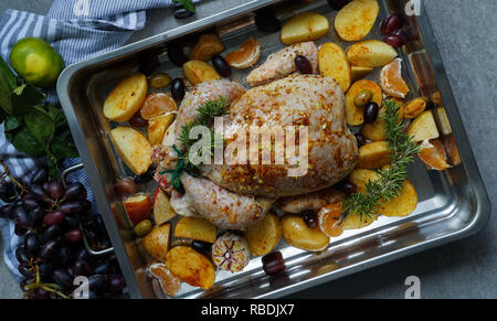 Gebackene Türkei oder saftiges Huhn mit goldenen knusprige Haut mit Trauben und Kartoffeln, Tangerine. Gebratenes Huhn in der auflaufform. Weihnachtsessen. Flach. Ansicht von oben Stockfoto