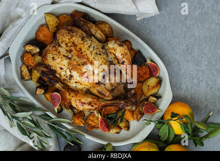 Gebackene Türkei oder saftiges Huhn mit goldenen knusprige Haut mit Trauben und Kartoffeln, Tangerine. Gebratenes Huhn in der auflaufform. Weihnachtsessen. Flach. Ansicht von oben Stockfoto