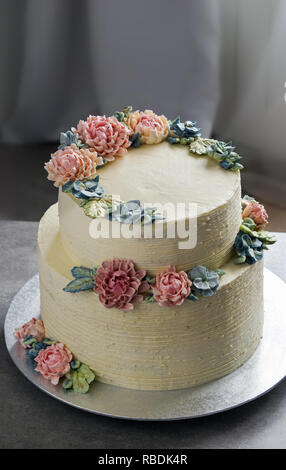 Große Hochzeitstorte, mit buttercream Blumen geschmückt, auf dem grauen Stein Hintergrund Stockfoto