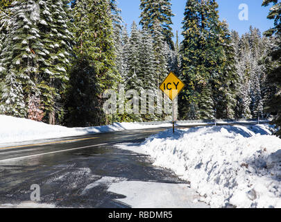 Vereisten Landstraße im verschneiten Wald im Winter. Die winterliche Landschaft mit schneebedeckten Straße. Straßensperrung Anmelden verschneite Straße in einem Winter Forest Stockfoto
