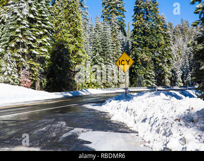 Vereisten Landstraße im verschneiten Wald im Winter. Die winterliche Landschaft mit schneebedeckten Straße. Straßensperrung Anmelden verschneite Straße in einem Winter Forest Stockfoto