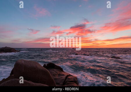 Rosa Himmel bei Sonnenuntergang auf den Wellen, die auf den Klippen von Capo Testa Santa Teresa di Gallura Province von Sassari-Sardinien-Italien-Europa Stockfoto