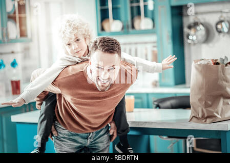 Können spielen. Gerne blonde Junge recken die Arme während freuen uns, Spielen mit Papa Stockfoto