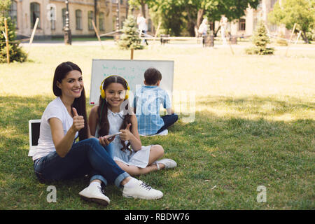 Kinder und Lehrer genießen in Park Stockfoto