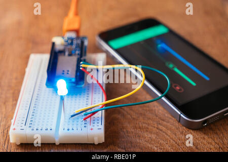 RGB-Led auf einem Steckbrett mit Mikrocontroller Board von einem Handy App gesteuert wird. Stockfoto