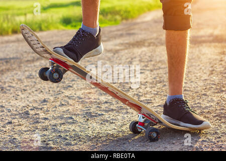 Der Kerl steht auf einem Skateboard ist auf der Straße schöne Muskelaufbau. Stockfoto