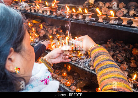 Nepalesische Frau Beleuchtung Kerzen an einem Tempel in Kathmandu, Nepal Stockfoto