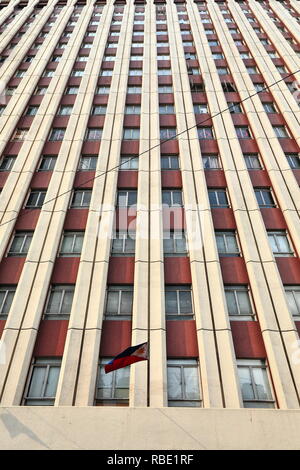 16-stöckiges, modernes Gebäude in Creme- und Granat Farben - symmetrische Reihen von Windows - Philippinische Fahne winken - Ecke von Jorge Bocobo Straße und Teodoro Stockfoto