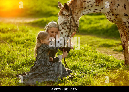 Schöne Frau und Mädchen umarmt das Pferd Stockfoto