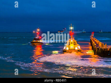Beleuchtete Boote segeln in der Nacht im Hafen von Vlissingen, die Anlegestelle Anlegestelle am Abend, Zeeland, Niederlande Stockfoto