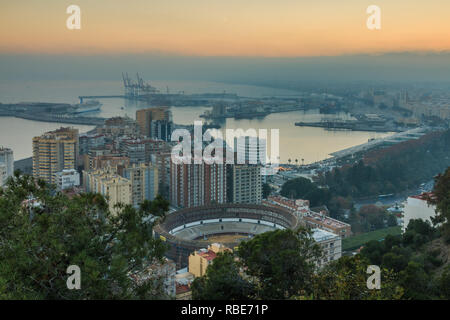 Spanische Stadt Malaga bei Sonnenuntergang. Hafen und der Altstadt mit einem Bull Ring von oben. Gebäude und Schiffe im Hafen gesehen werden kann. in der backgroun Stockfoto
