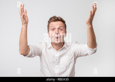 Gerne Mann sieht mit Erstaunen und Verwunderung Gesicht, Hände hoch. Stockfoto