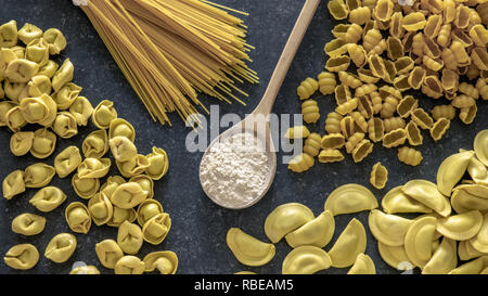 Verschiedene Nudeln und Mehl auf dunklem Stein Hintergrund. Glutenfreie Lebensmittel Konzept. Stockfoto