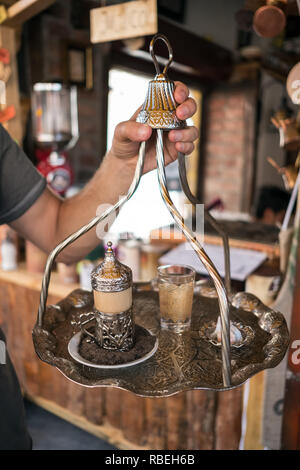 Traditionelle türkische Kaffee serviert in einem wunderschönen Metall Schale am heißen Sand mit einem Glas Wasser und Turkish Delight im Outdoor Cafe in Ankara, Türkei Stockfoto
