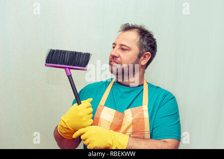 Emotionale bärtiger Mann mit einem Besen. Hellen Hintergrund. Stockfoto