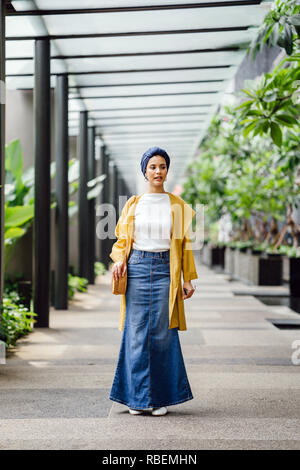 Porträt eines großen, schönen und eleganten im Nahen und Mittleren Osten arabische Frau in einem turban und ein Pastell Outfit stehen auf einer Straße in der Stadt. Stockfoto