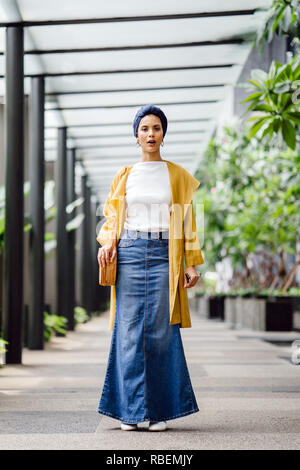 Porträt eines großen, schönen und eleganten im Nahen und Mittleren Osten arabische Frau in einem turban und ein Pastell Outfit stehen auf einer Straße in der Stadt. Stockfoto